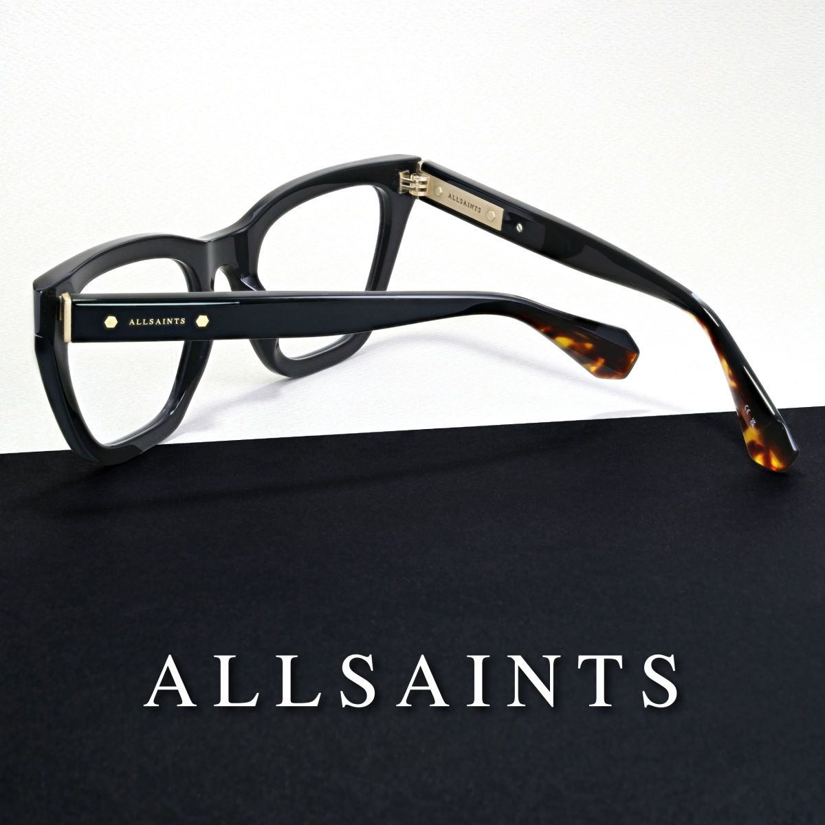 Thick black frames on a black and white background, facing away to show the temple. AllSaints logo in white at the bottom of the image.
