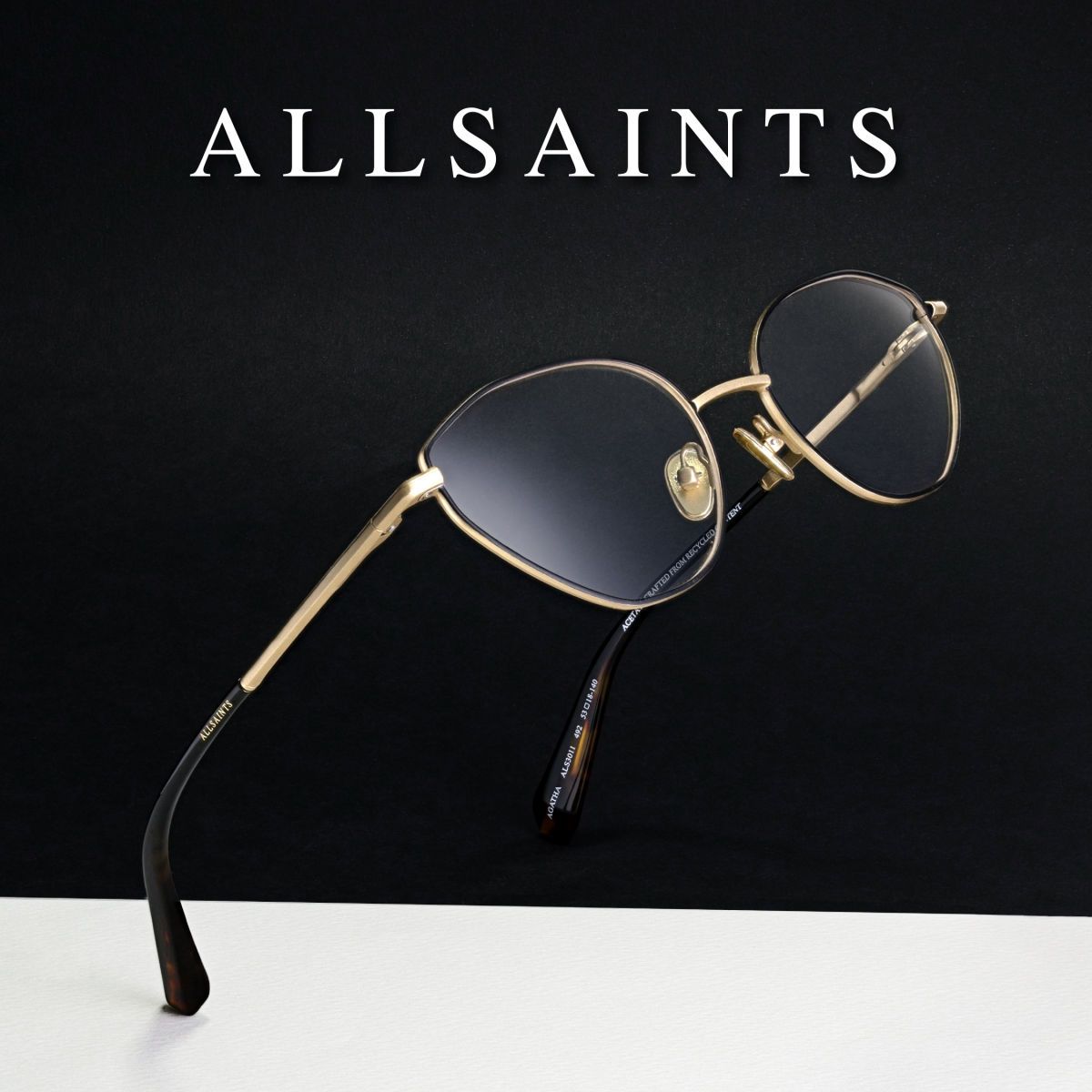 Gold frames on a black and white background, facing to the upper left to show the gold and black temple. AllSaints logo in white at the top of the image.