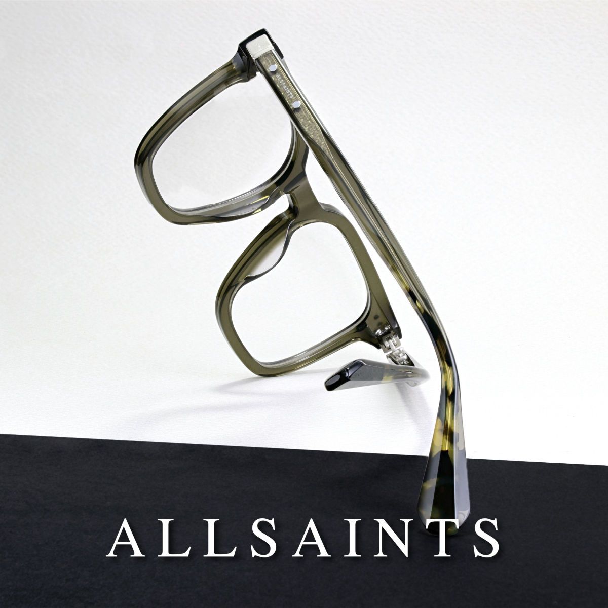 Olive green frames against a white background. Frames are at an odd angle facing away from the camera to highlight the temple. AllSaints logo runs along the bottom in white text againts a black background.