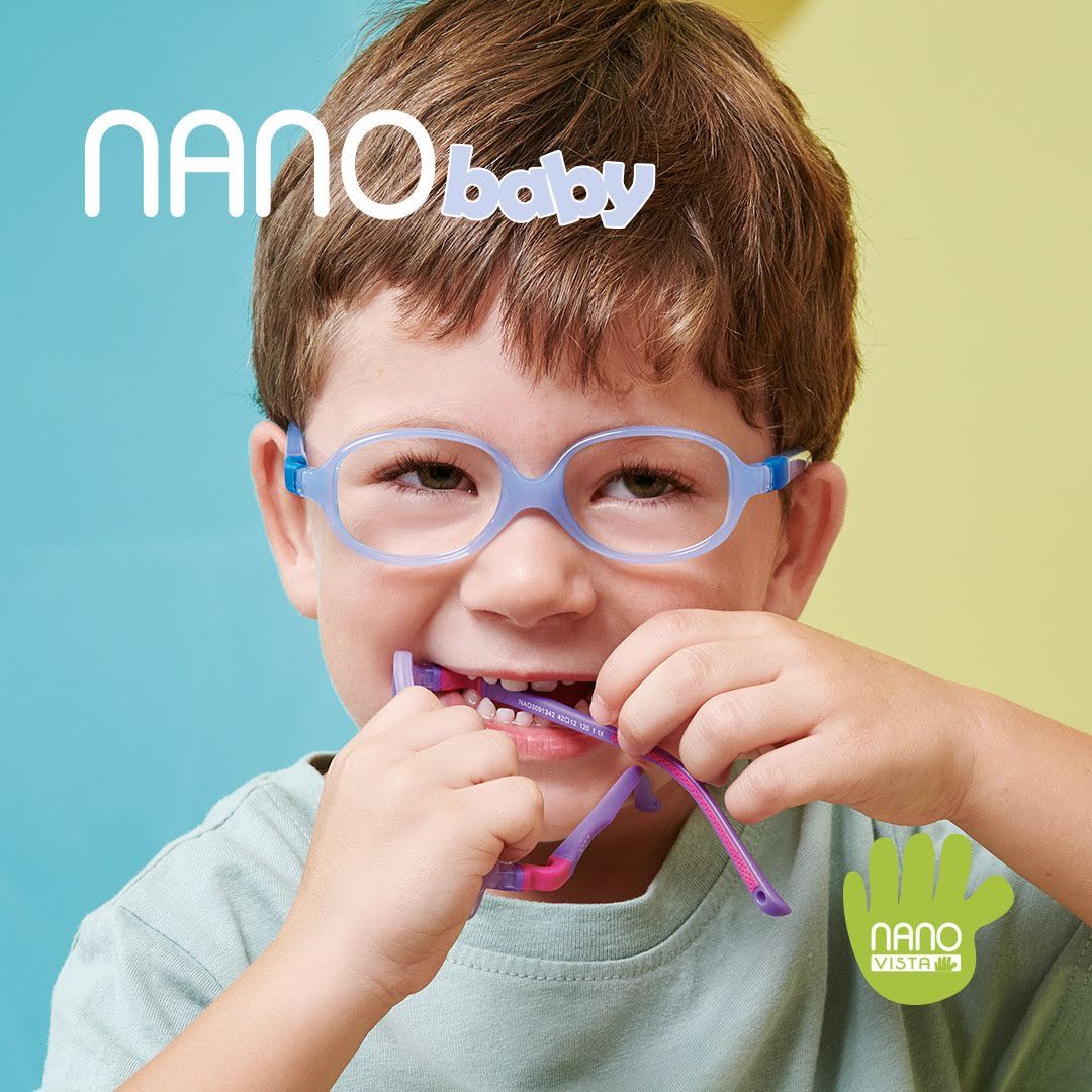 Young boy with short brown hair against a half blue half yellow background, wearing pale blue frames while biting purple frames. Nano Baby logo located in the upper left, Nano Vista logo located on bottom right.