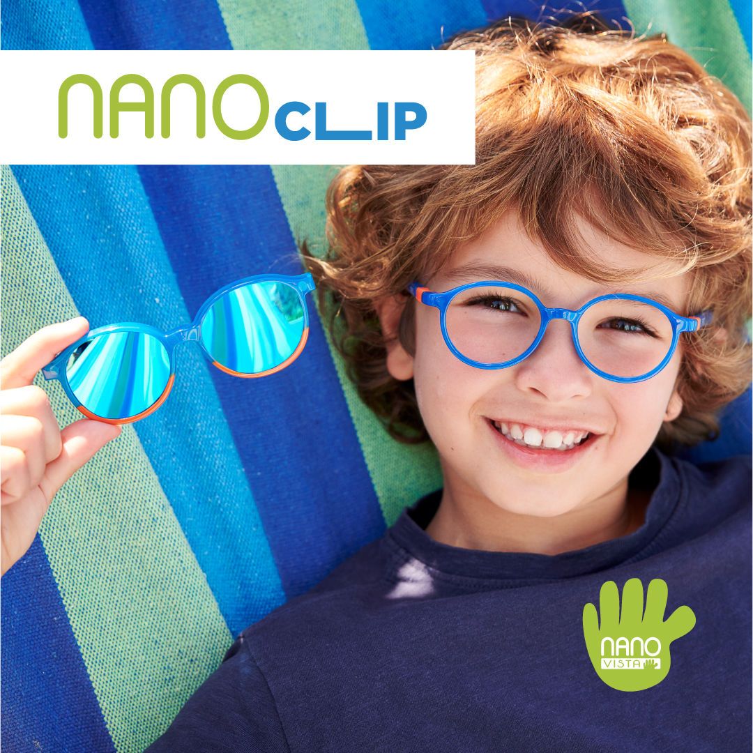 Boy with curly hair and a dark blue shirt, lounging in a striped hammock, wearing bright blue round frames and holding up a pair of clip on sunglasses. Nano Clip logo located in the upper left, Nano Vista logo located on bottom right.