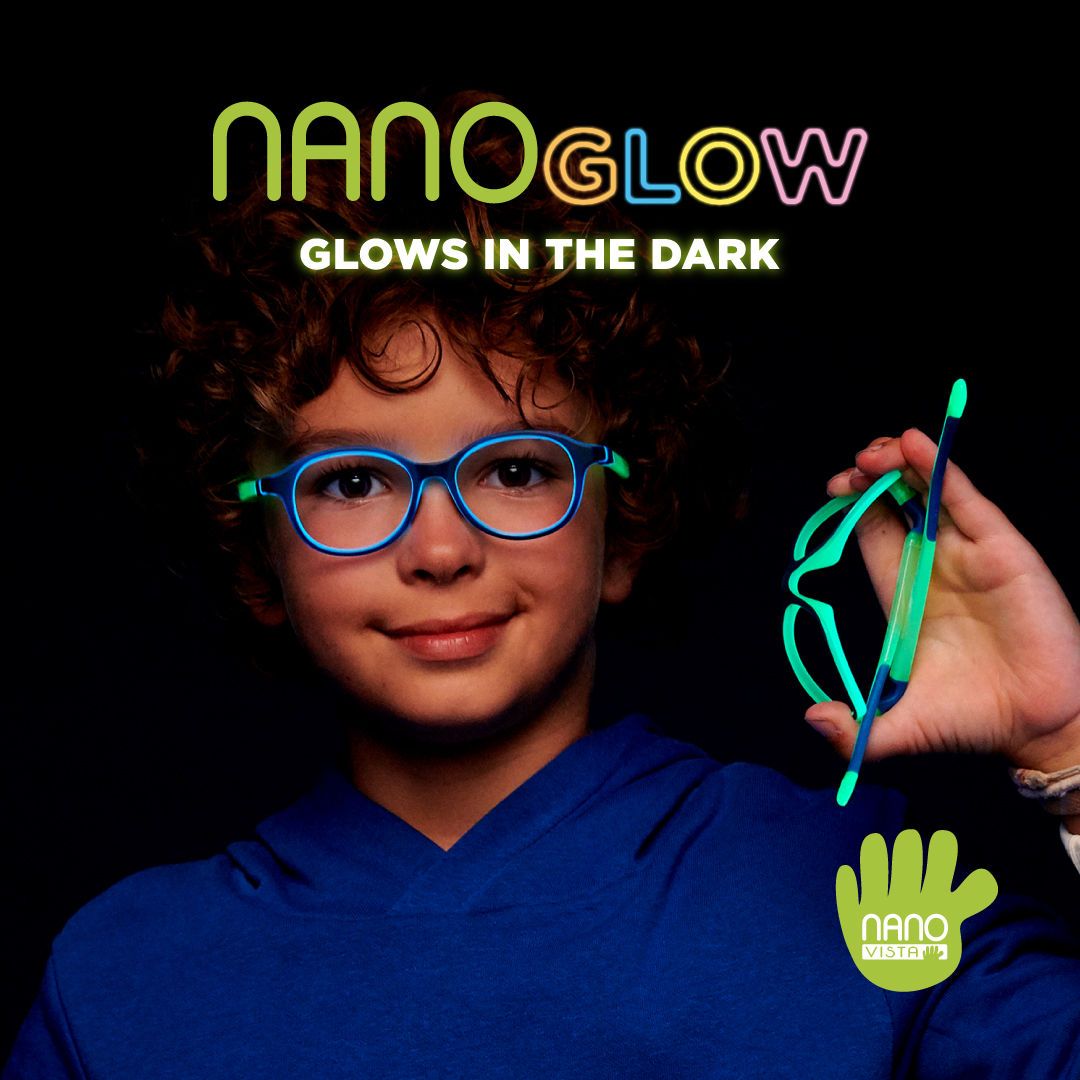 Young boy with curly brown hair and a blue hoodie stands in the dark weaing glowing blue frames, and bending a different pair of frames. Nano Glow Glows in the dark is written across the top of the image, Nano Vista logo located on bottom right.