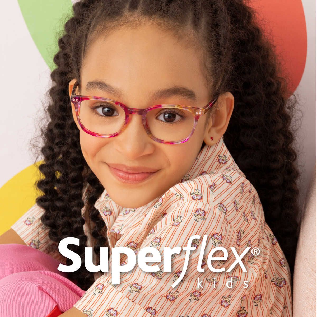 Close-up of young child's smiling face showing off pink patterned frames